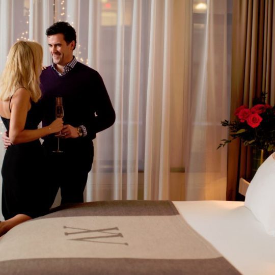 beautiful couple standing by a XV Beacon bed with roses to the side